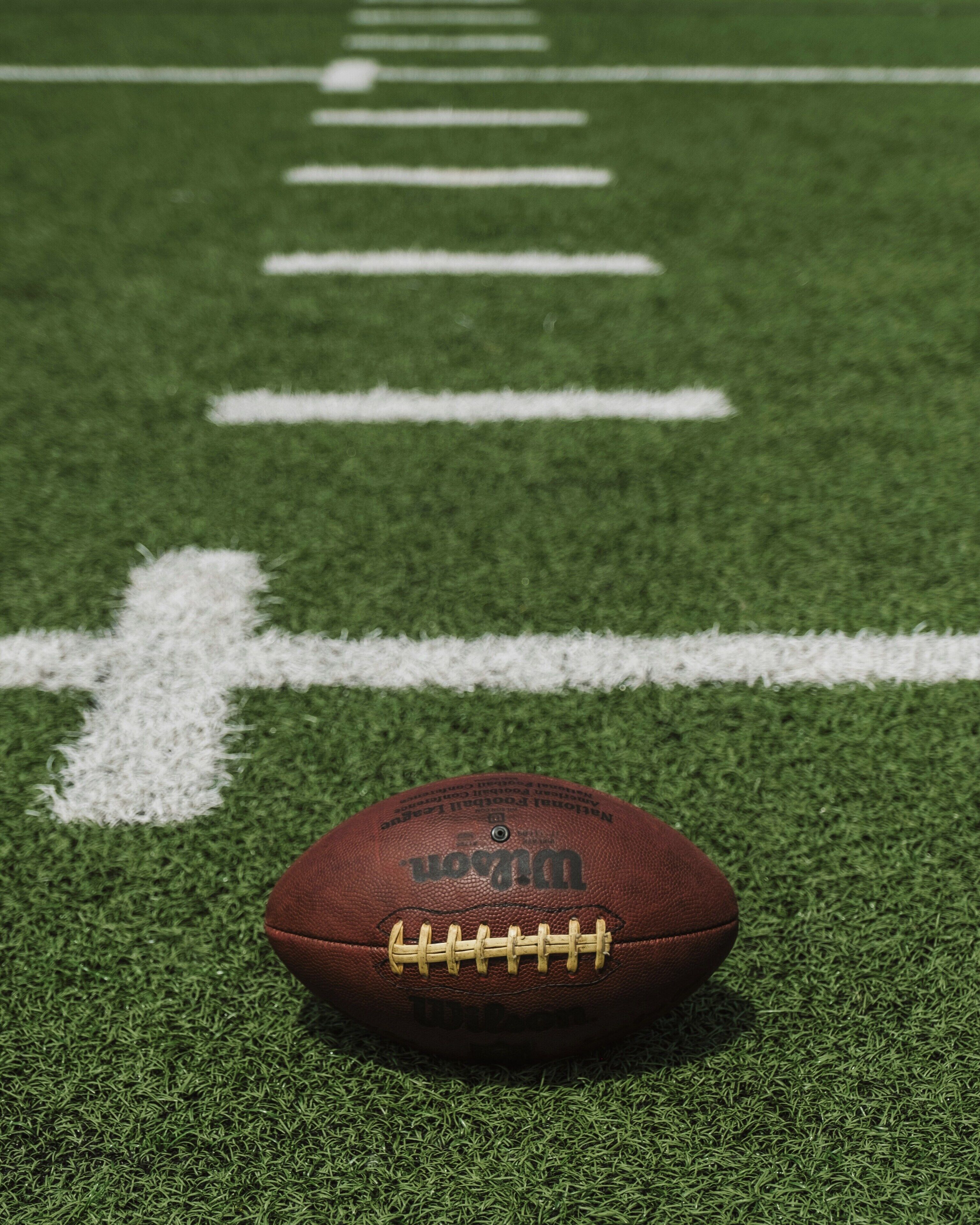 A football on a green field with white lines.