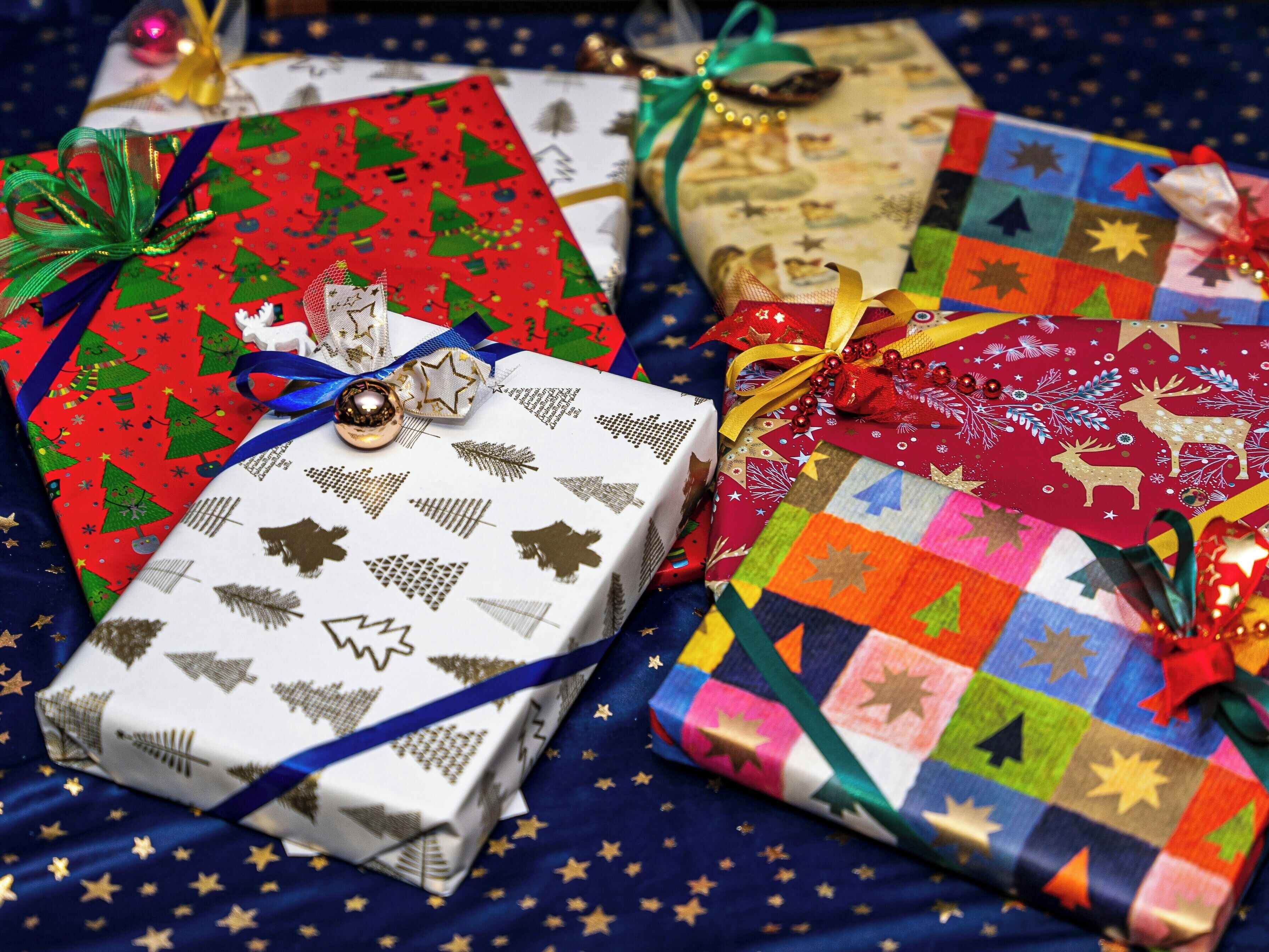 Three wrapped gifts with ribbons and bows on a fabric background with star patterns.