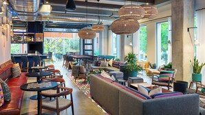 A modern lounge area with seating, tables, and hanging wicker lamps. - Aloft by Marriott Austin Downtown (Austin)