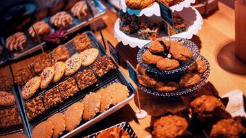 Diversas opciones de productos horneados expuestos en bandejas y soportes, entre ellos galletas y brownies.