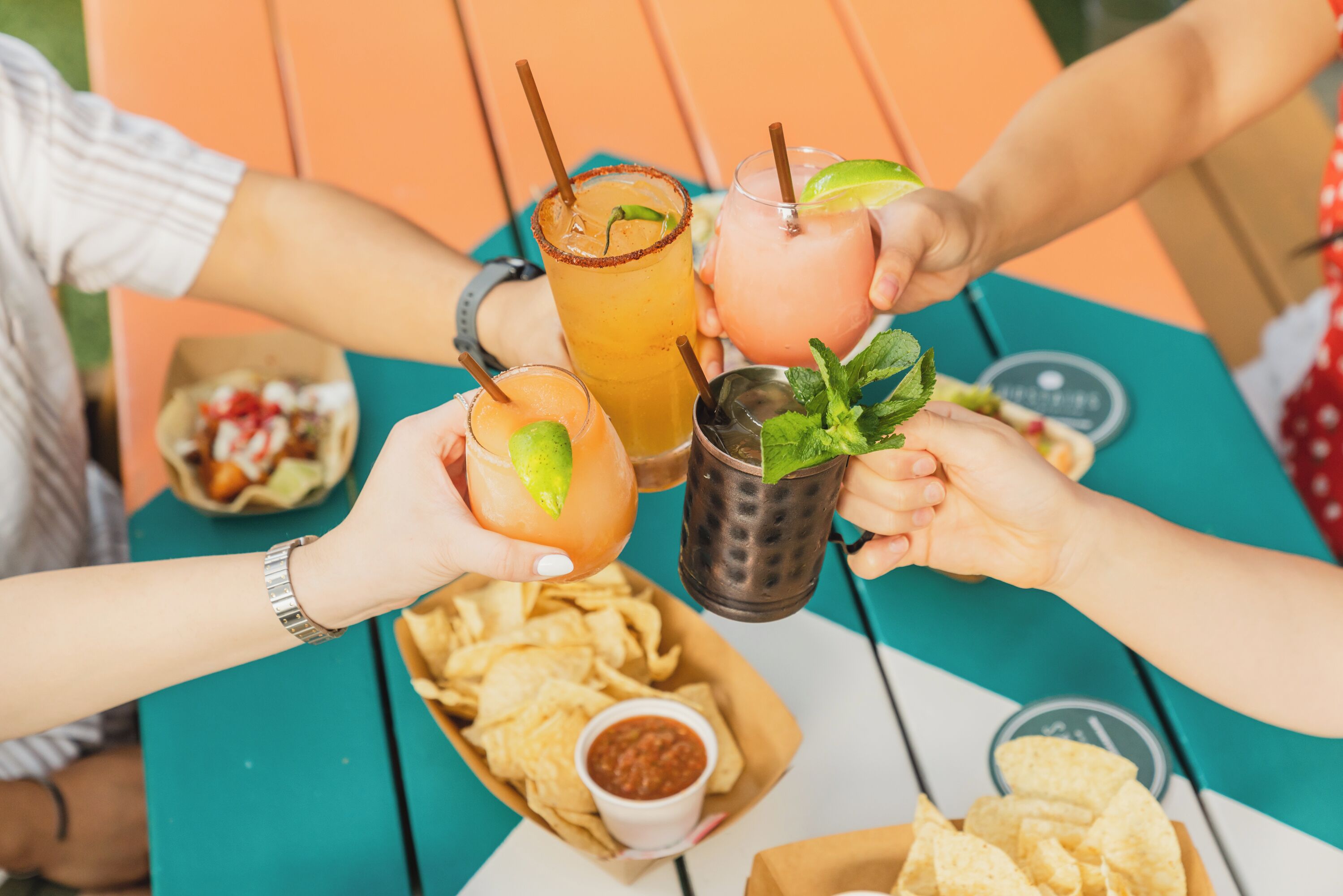 Un grupo de personas brindando con bebidas y papas fritas en una mesa.