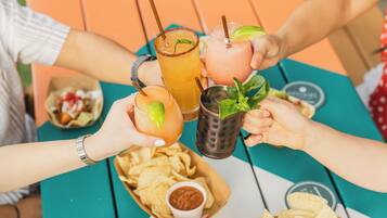 Un grupo de personas brindando con bebidas y papas fritas en una mesa.