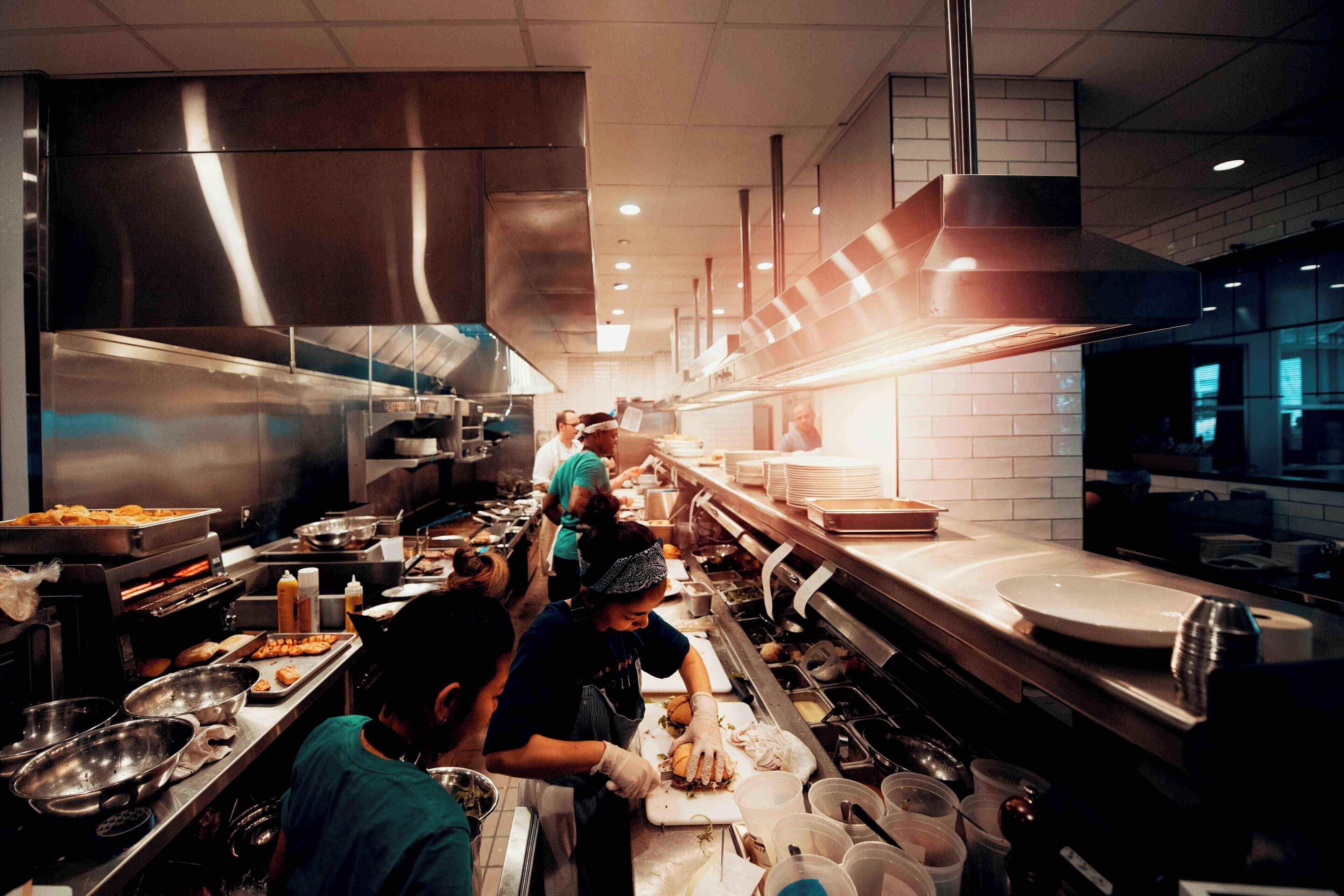 Une cuisine professionnelle très fréquentée, dotée d’appareils en acier inoxydable et d’un long comptoir.