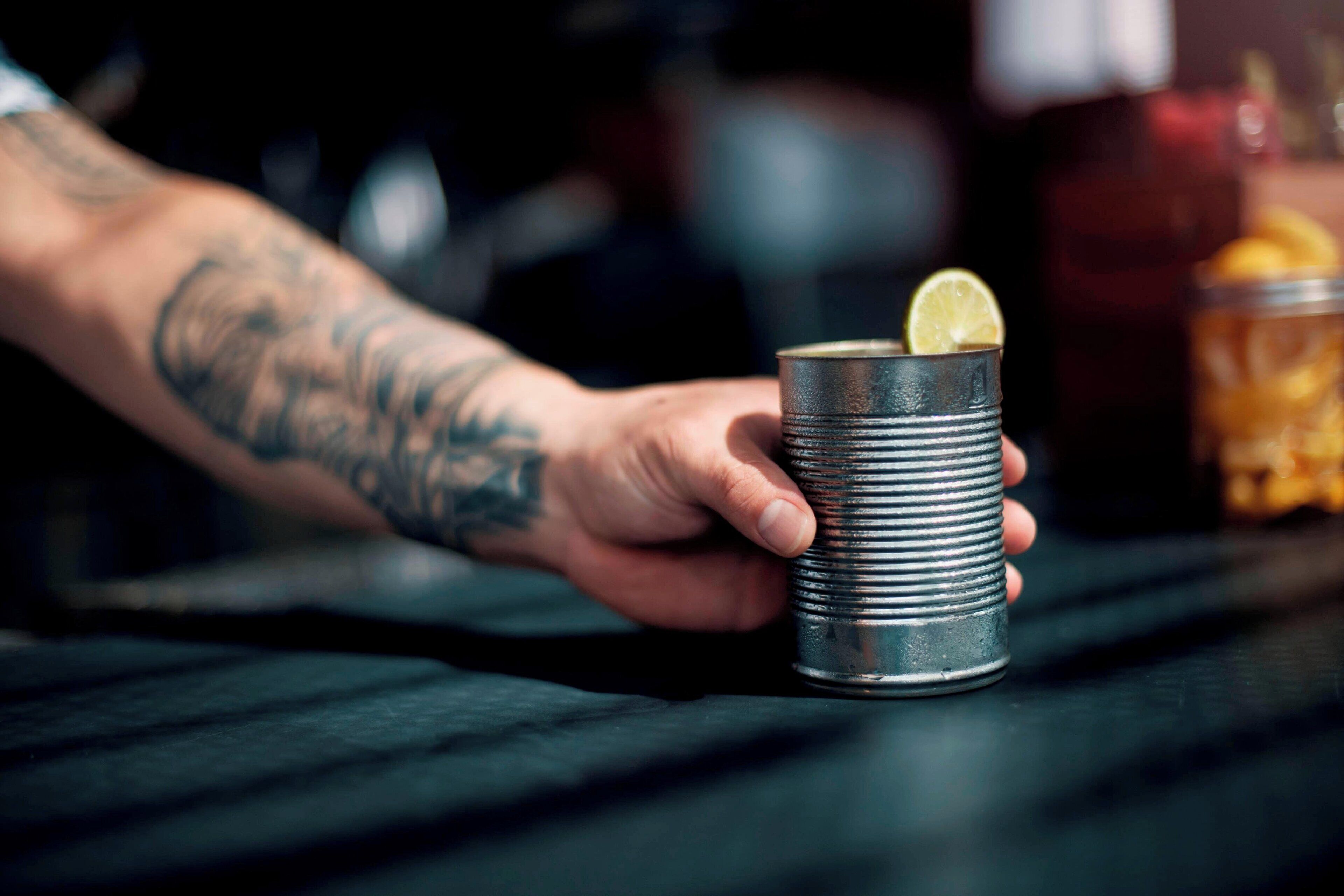 A hand holding a metal cup with a lemon slice.