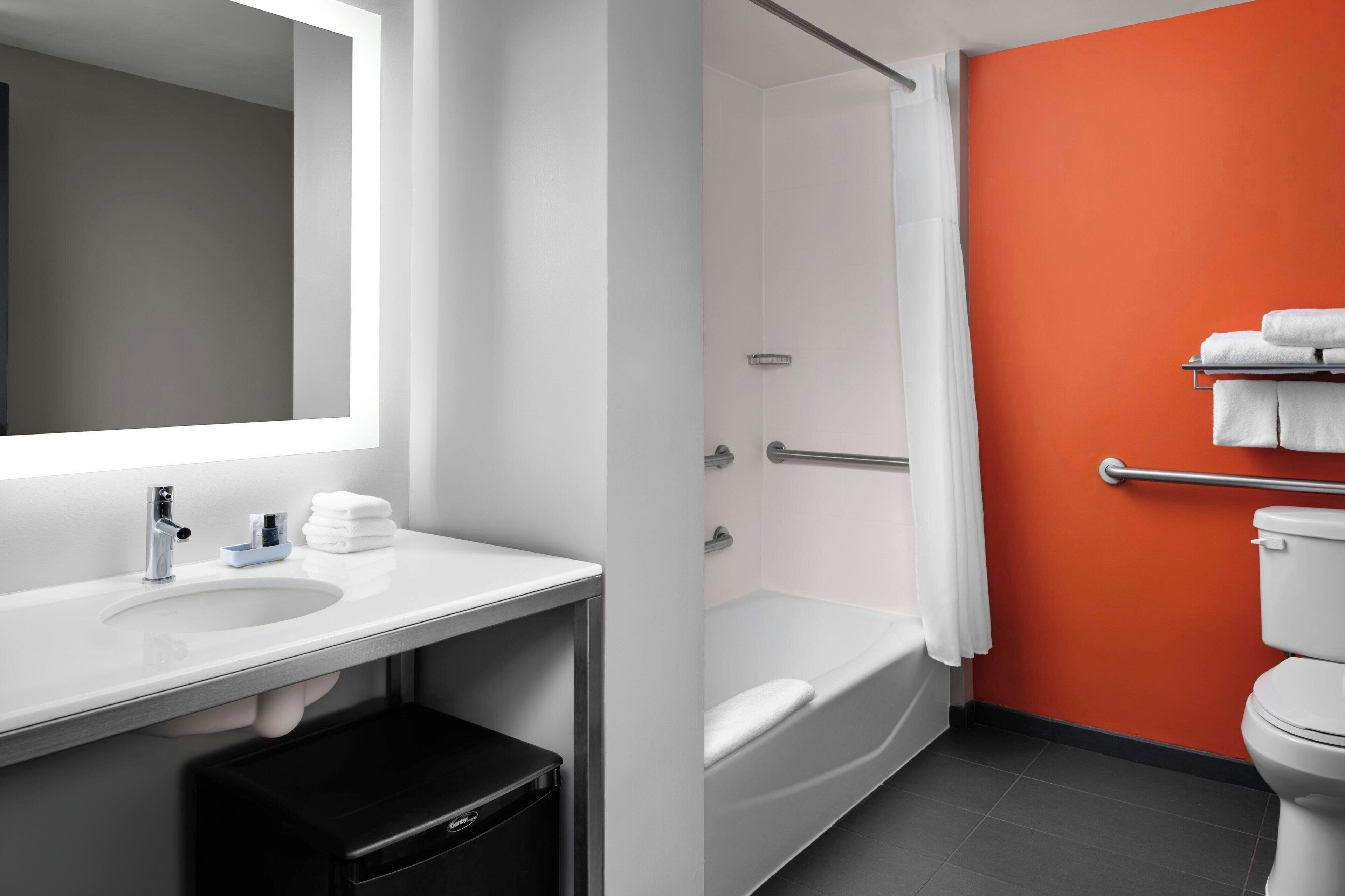 A modern bathroom with a white sink, mirror, and white toilet.