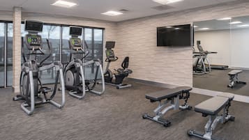 Un gimnasio con cintas de correr, elípticas y bancos de pesas.