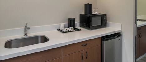 A modern kitchen with a stainless steel sink, a black coffee maker, a microwave, and a dishwasher.