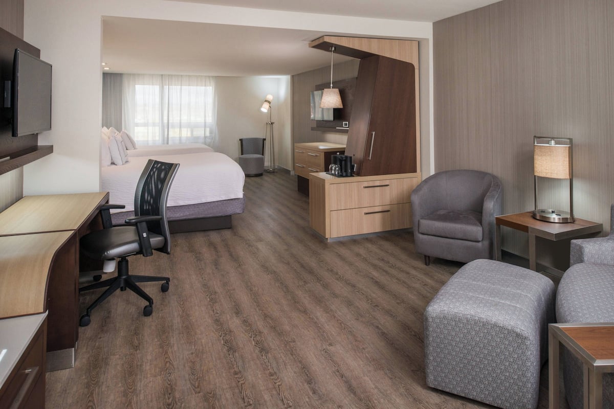 Una habitación de hotel con cama, escritorio, silla, reposapiés y televisor.