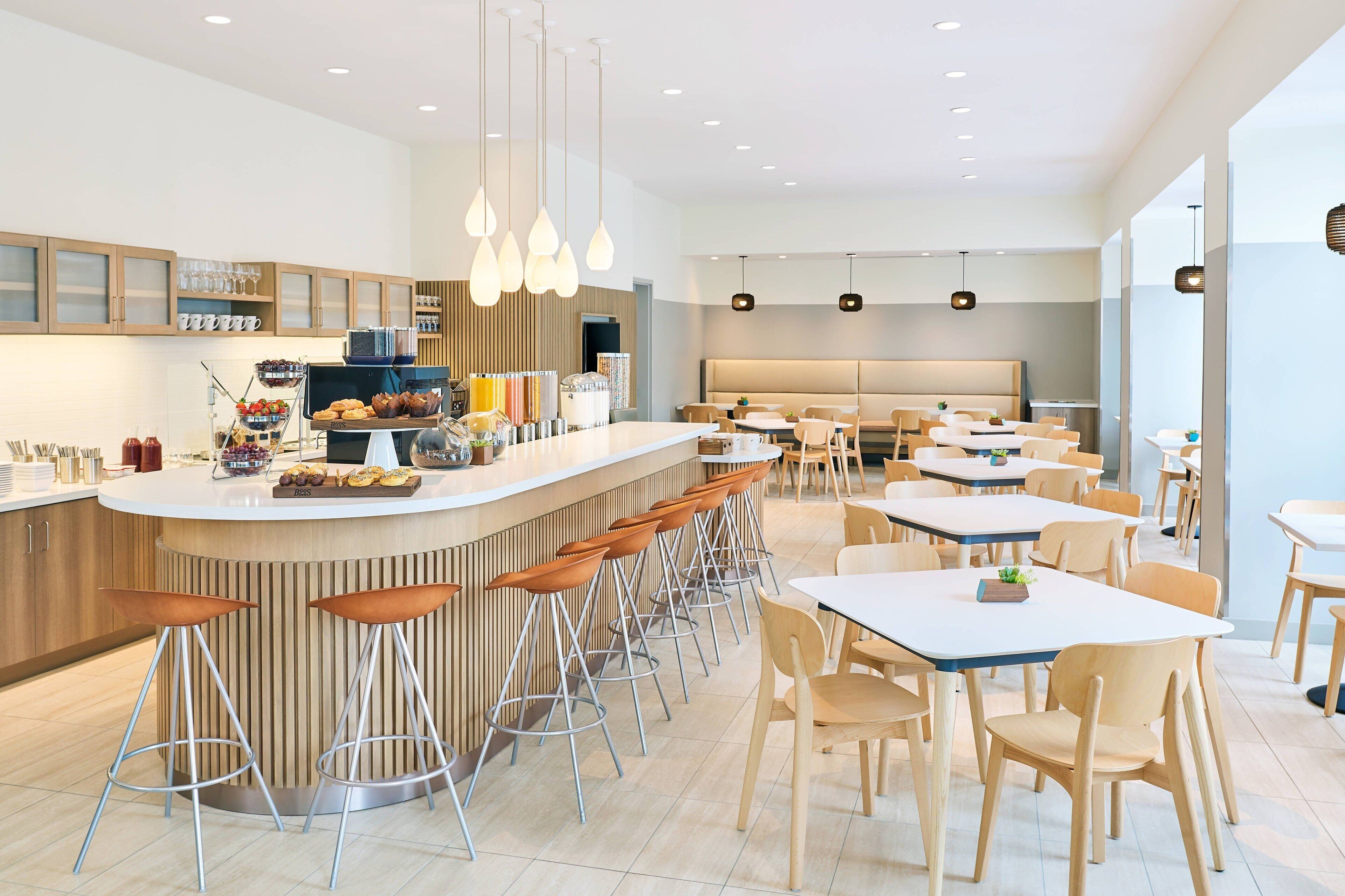 A modern restaurant with a central bar, multiple seating areas, and a variety of food and drink options.