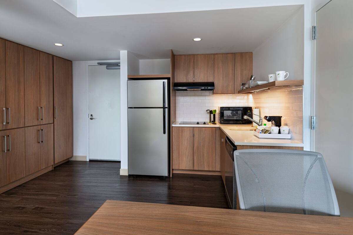 Una cocina moderna con armarios de madera, un refrigerador de acero inoxidable y un microondas.