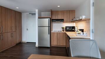 A modern kitchen with wooden cabinets, a stainless steel refrigerator, and a microwave.