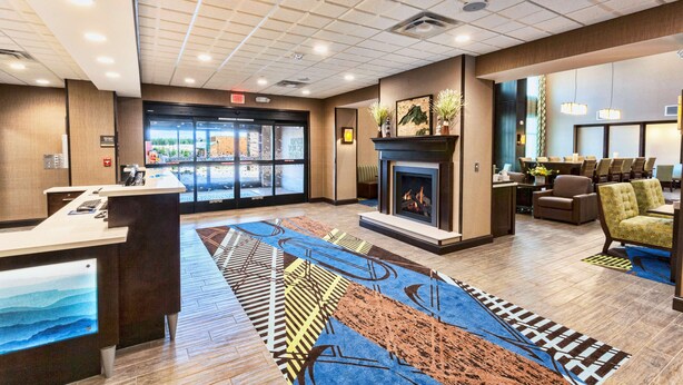 A hotel lobby with a reception desk, a fireplace, seating area, and a view of the outside. - Hampton Inn & Suites Duluth North/Mall Area (Duluth)