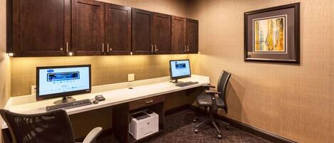 A hotel office with two computer workstations, a printer, and a framed picture on the wall.