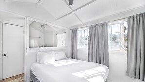 A modern hotel room with a large bed, a built-in wardrobe, a window with curtains, and a ceiling light. - Hermosa Hotel (Avalon)