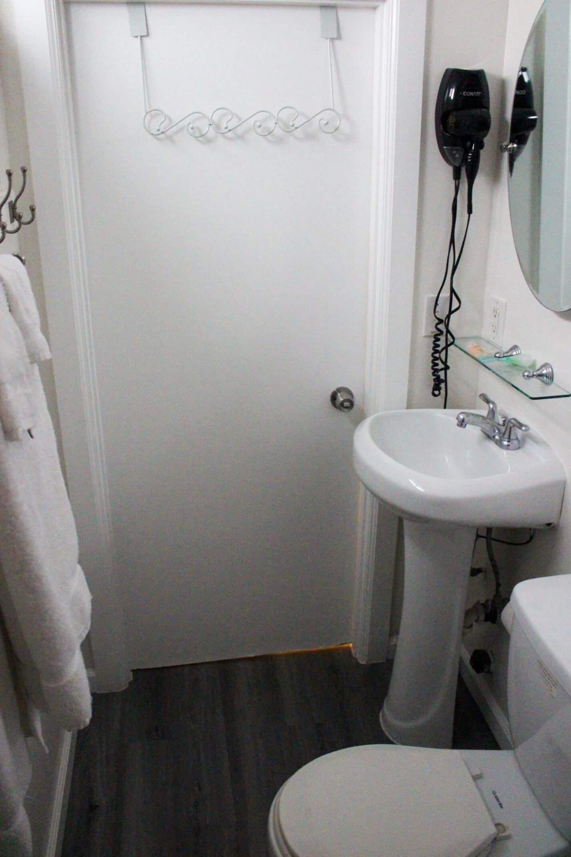 Un baño con un lavamanos blanco, un inodoro y un perchero para toallas.