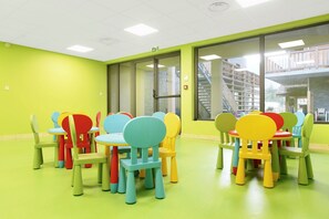 A brightly colored room with green walls and a green floor, featuring multiple colorful chairs and tables arranged in a casual setting. - Cozy Balcony Apartment (La Clusaz)