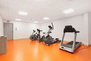 A fitness room with three stationary bikes and a treadmill.