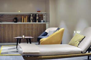 A modern living room with a sofa, armchair, and a small table with magazines.