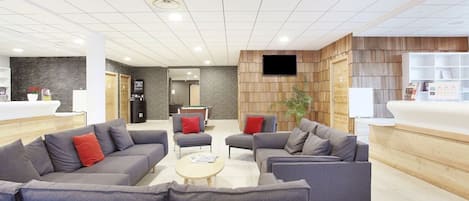 A modern lobby with sofas, a pool table, and a reception desk.