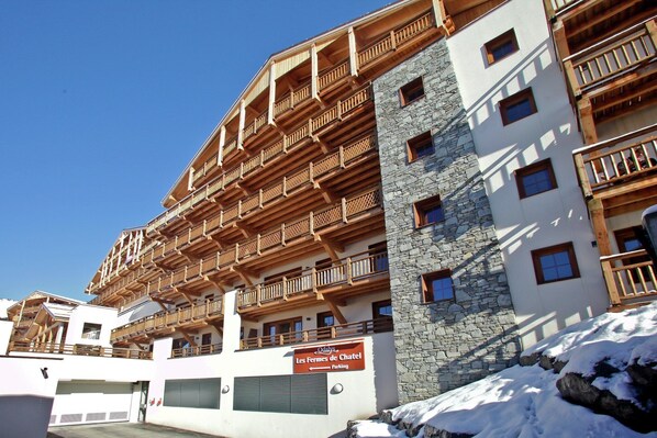 A multi-story hotel with wooden balconies and stone facade.