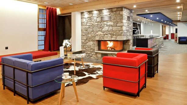 A modern living room with a stone fireplace, red and blue sofas, a glass coffee table, and a cowhide rug. - Chalet in Chatel by Super Chatel Gondola (Chatel)