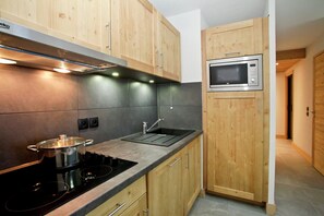 A compact kitchen with wooden cabinets, a built-in microwave, and a stove.