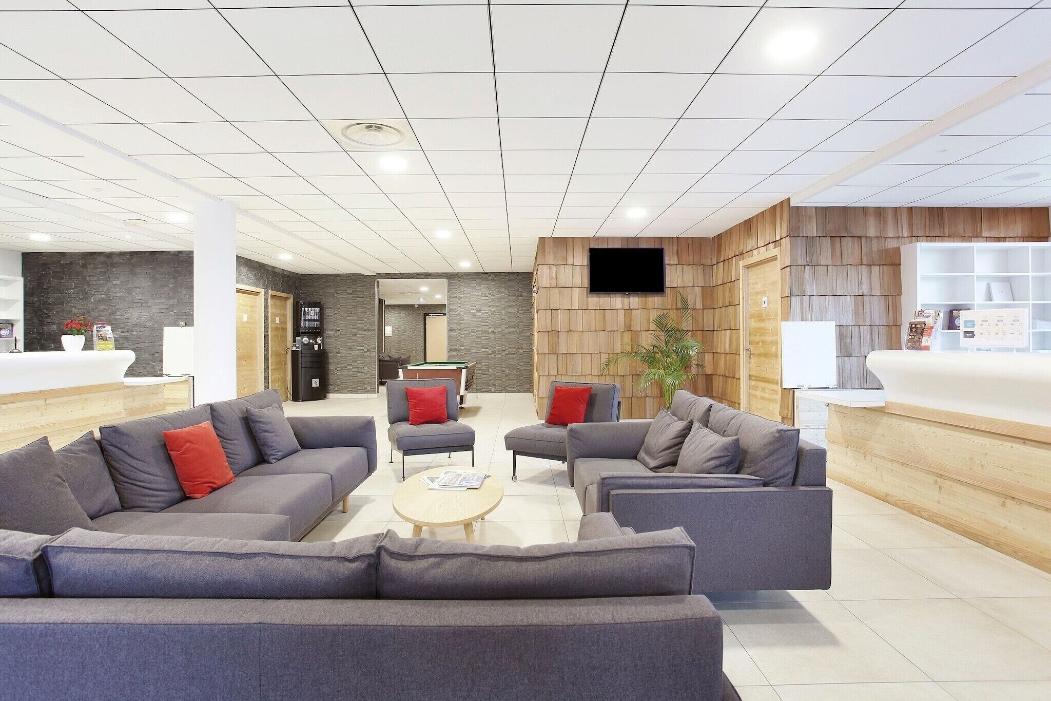 A modern lobby with sofas, a pool table, and a reception desk.