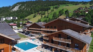 Un complexe hôtelier doté de bâtiments en bois, d’une piscine et situé dans un cadre montagneux.