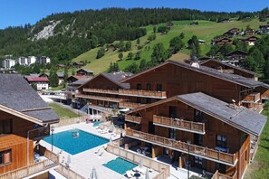 Ein Resort mit Holzhäusern, einem Schwimmbad und einer Bergkulisse.