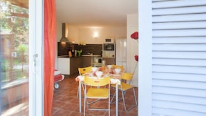 A compact kitchen with modern appliances, a dining area with yellow chairs, and a view of the outdoors. - Holiday Home in Corsica by the Sea (Poggio Mezzana Corse)