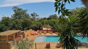 A pool area with wooden deck and lounge chairs, surrounded by trees and greenery. - Holiday Home in Corsica by the Sea (Poggio Mezzana Corse)