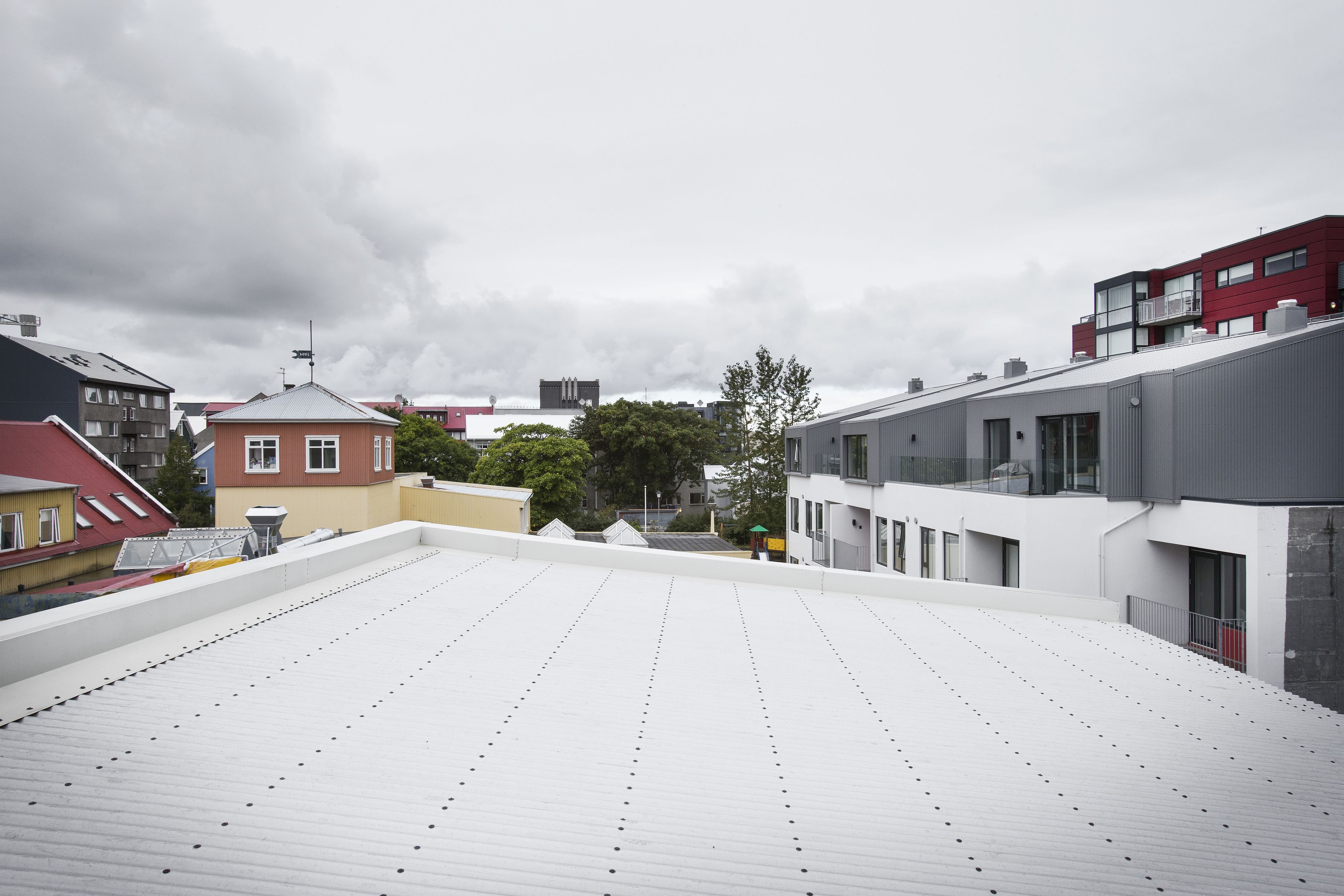 A rooftop terrace with a white roof, surrounded by buildings with red and grey facades.