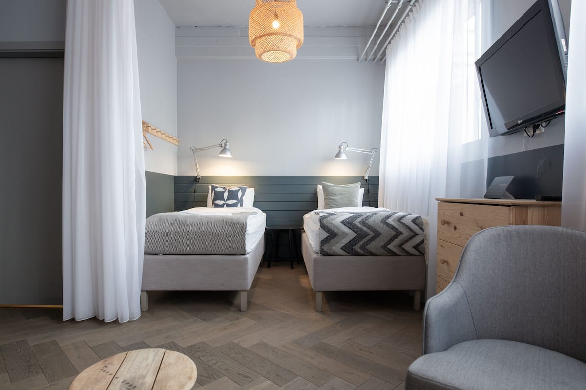 A bedroom with two beds, a TV, and a desk.