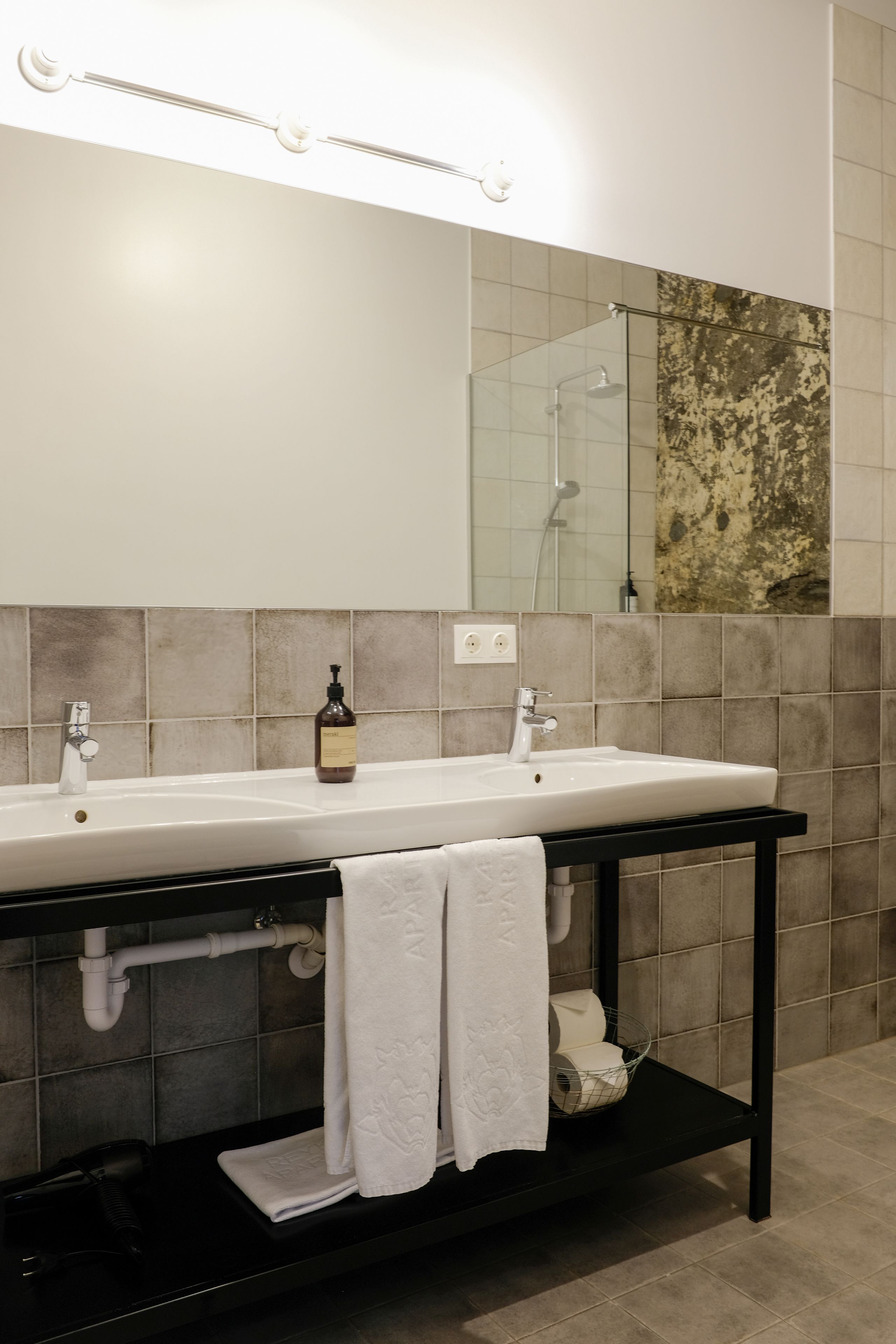 A bathroom with a double sink, a mirror, and a shower.