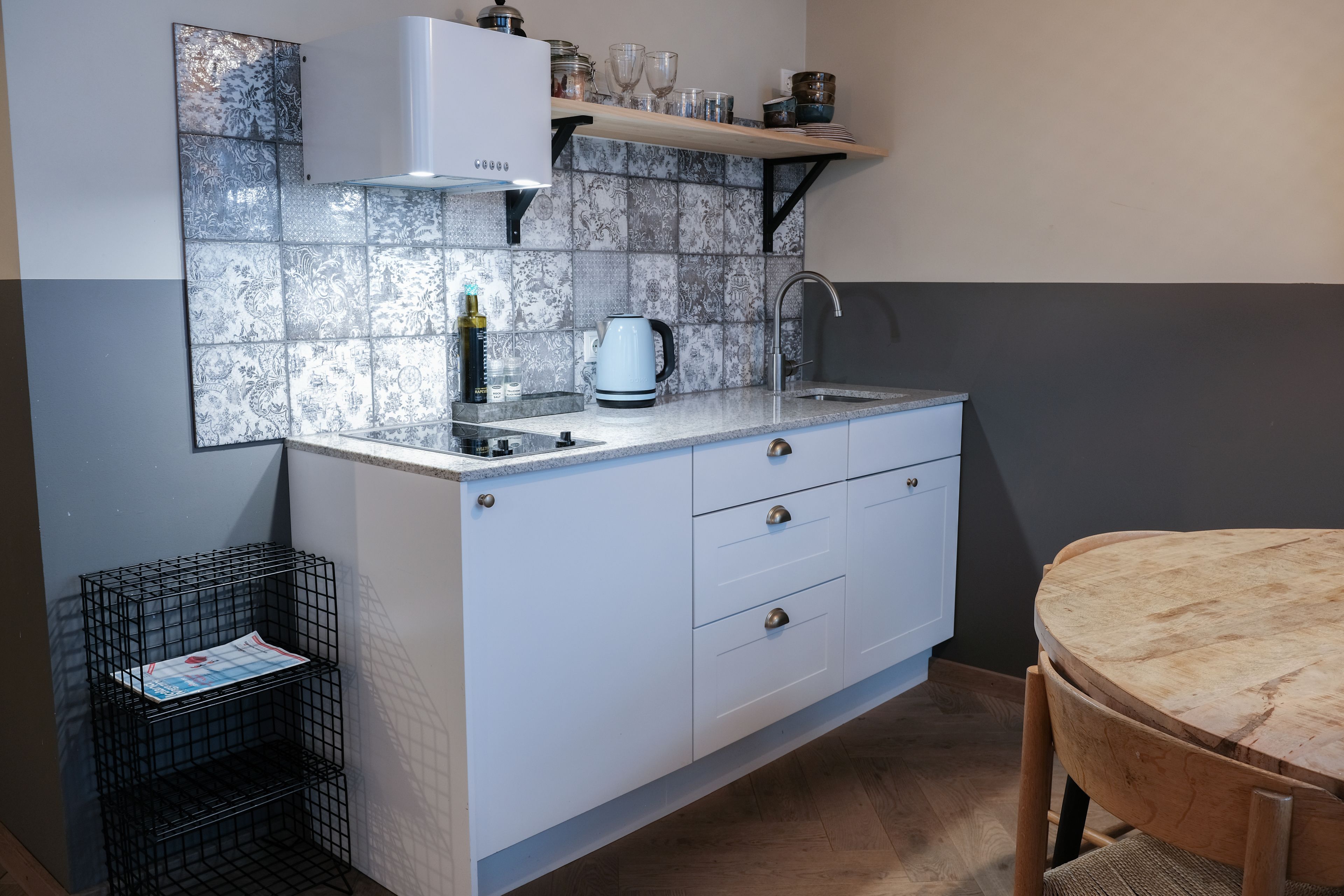 A compact kitchen with a sink, kettle, and a small shelf above it.