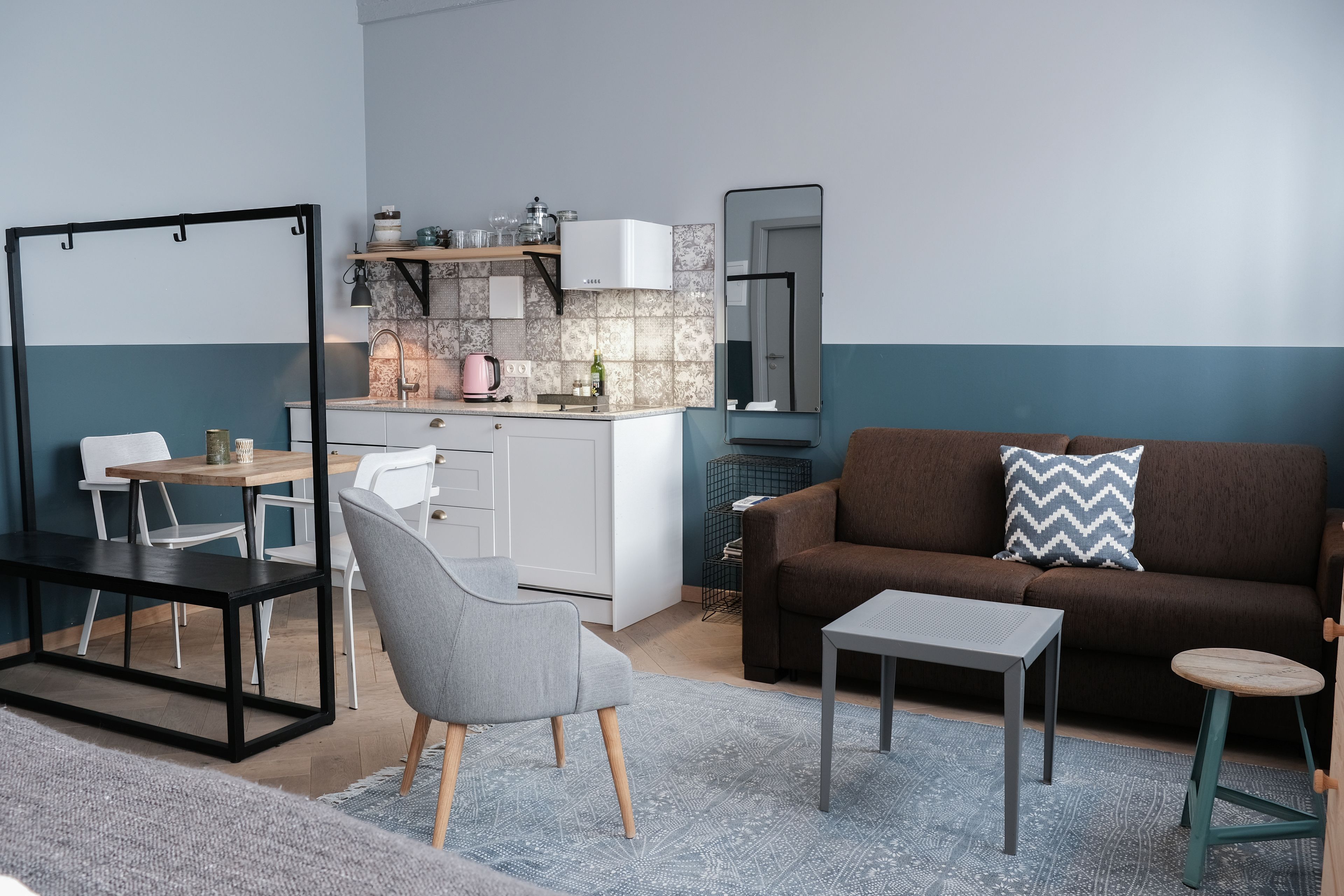 A compact living space with a kitchenette, a sofa, a dining table, and a chair.