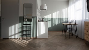 A modern kitchen with a white island, a hanging pendant light, and a dining area with a chair and table.