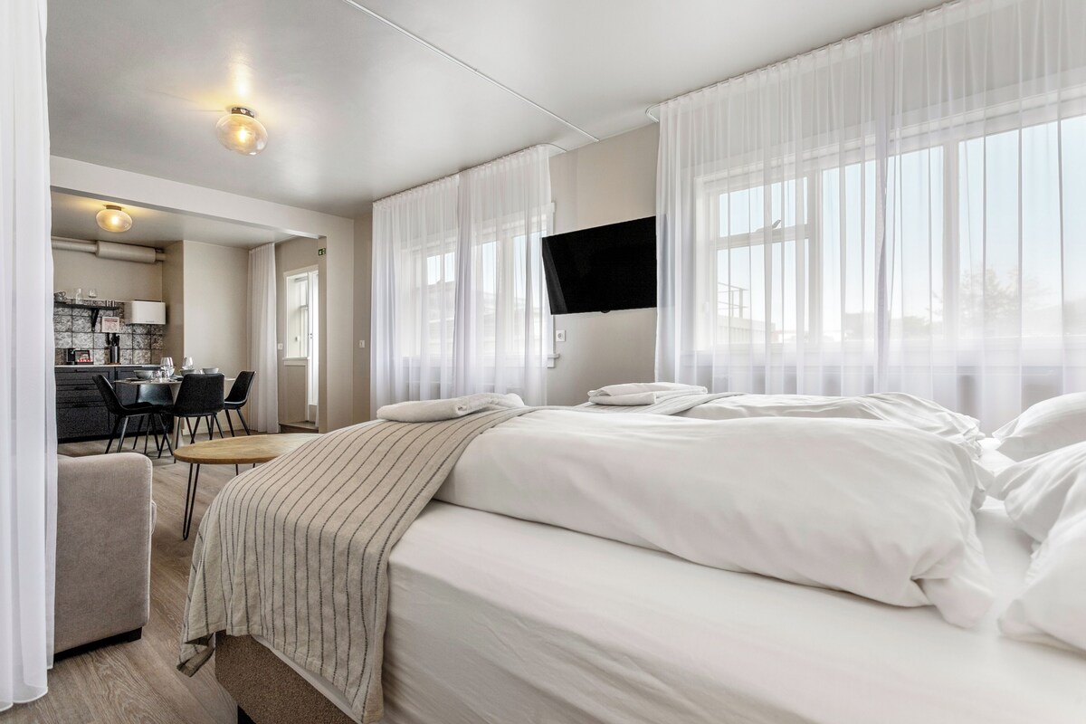 A hotel room with a bed, a desk, and a chair.