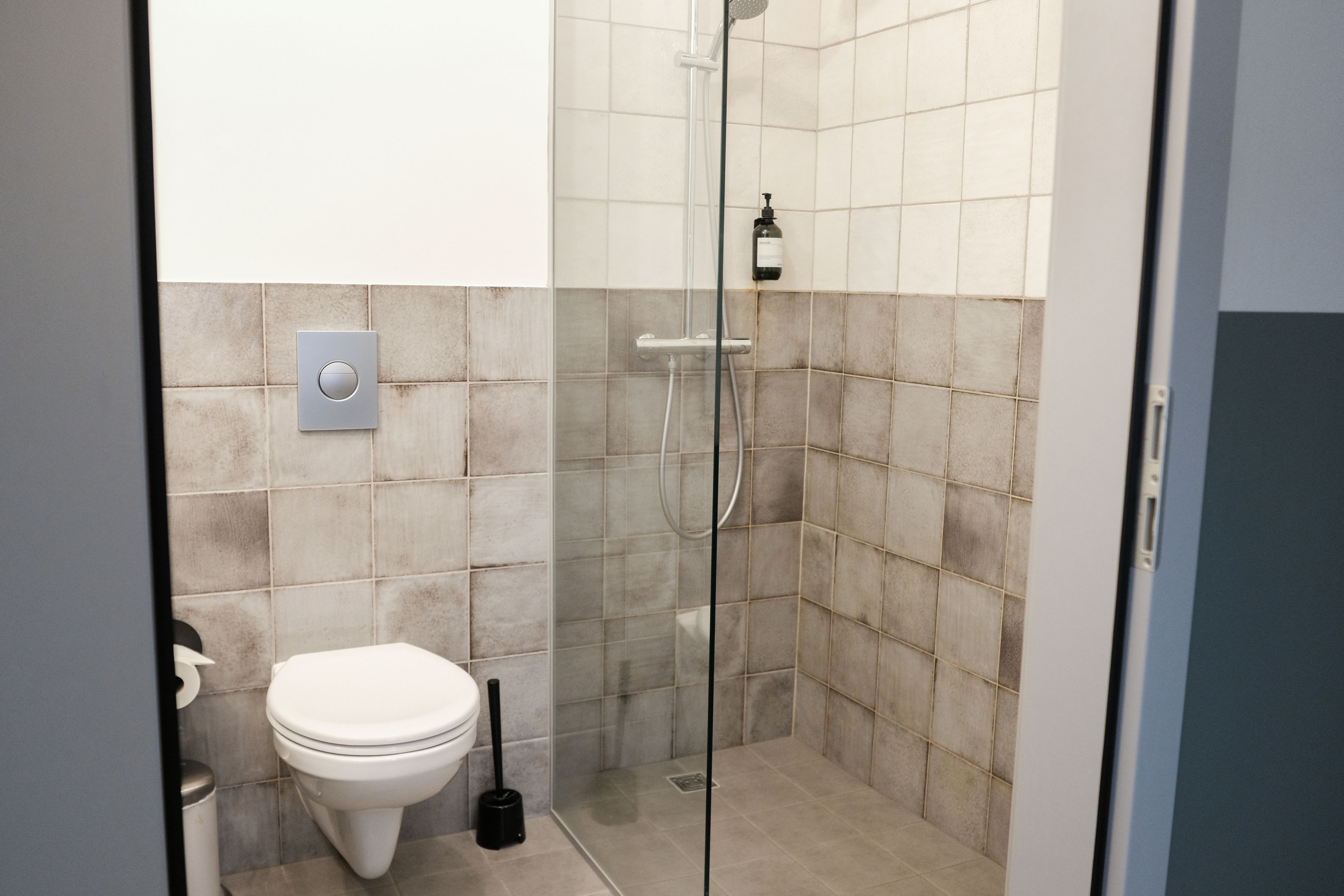 Un bagno moderno con il water, una doccia con pareti in vetro e un asciugamani ad aria.