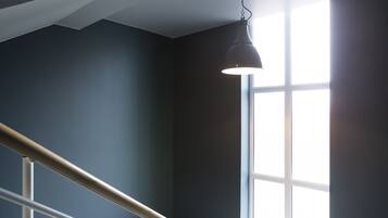Eine Treppe mit Metallgeländer, einer dunklen Wand und einem Fenster mit Tageslicht.