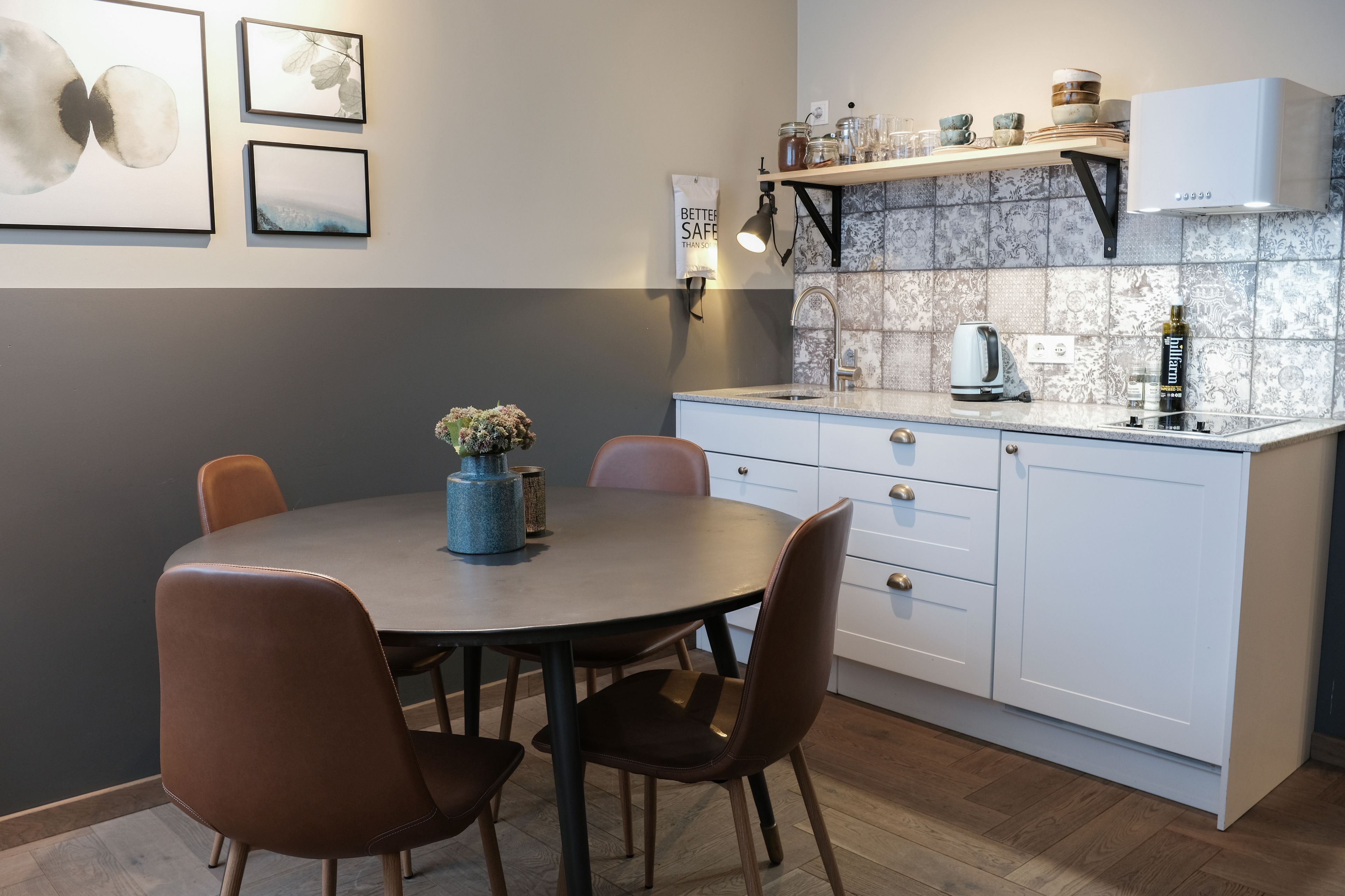 Et moderne køkken med hvide skabe, en bordplade og et spiseområde med et bord og stole.