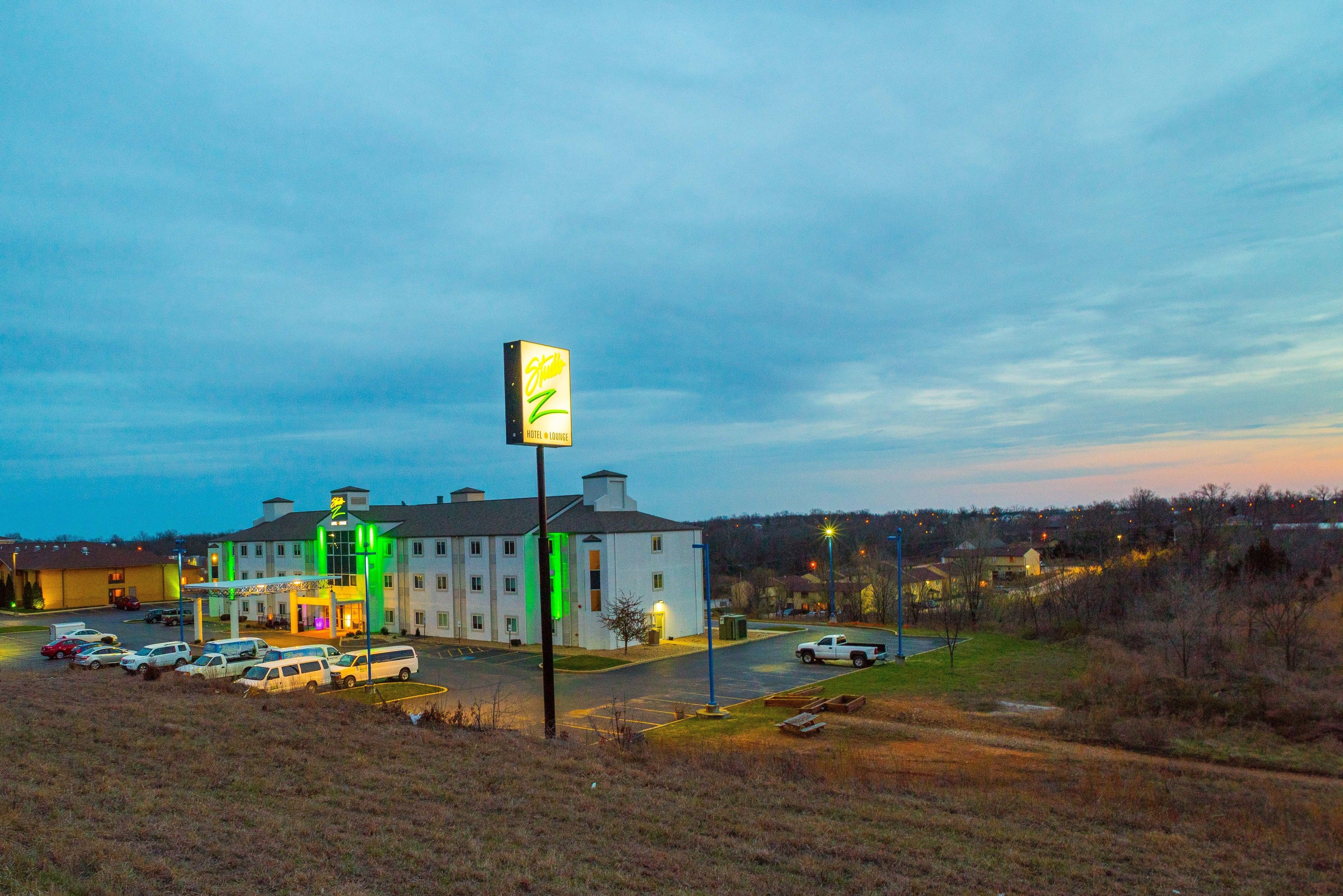 A hotel with a large sign, multiple parking spaces, and a well-lit entrance.