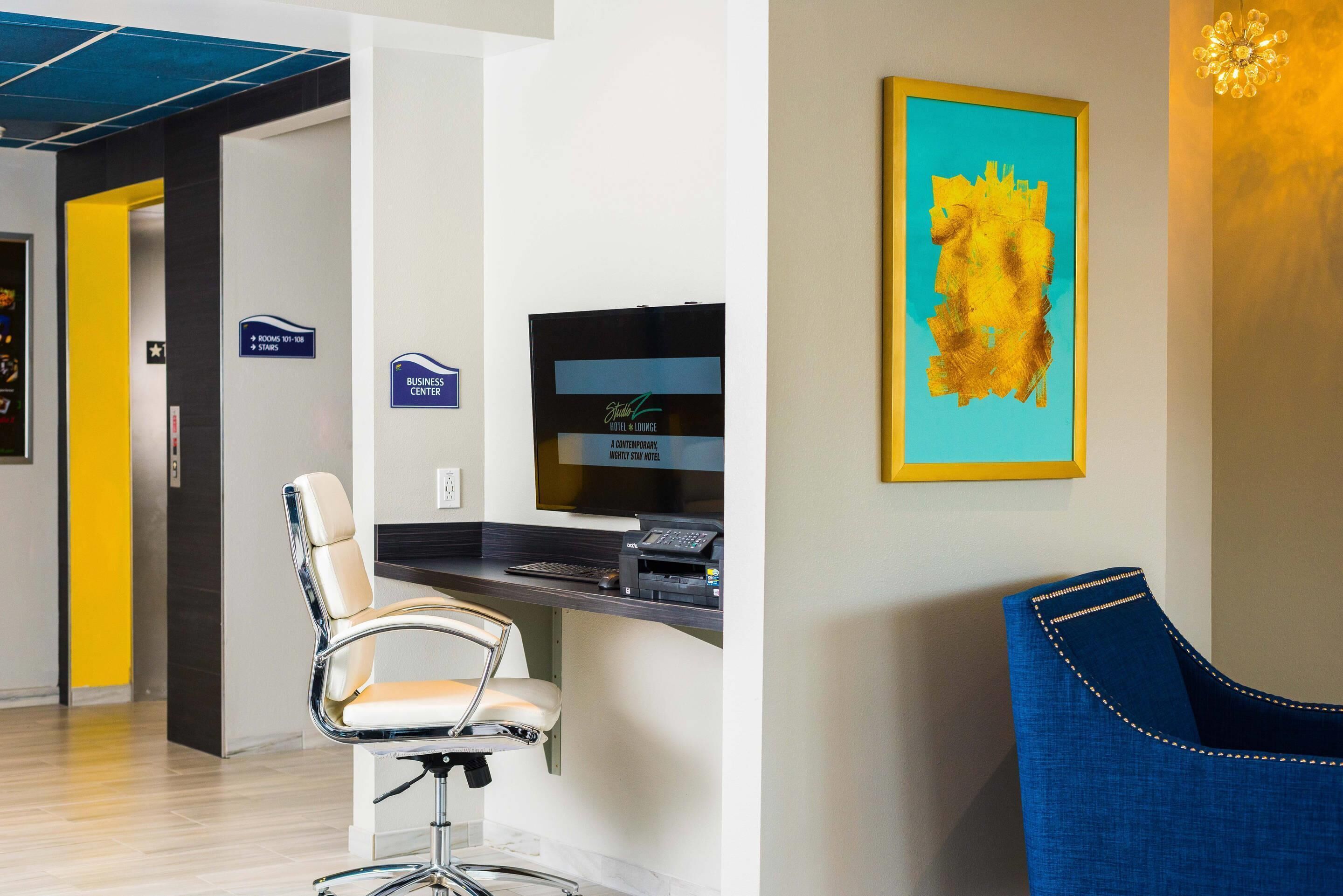 A reception area with a modern chair, a desk with a computer and phone, and a framed abstract painting on the wall.