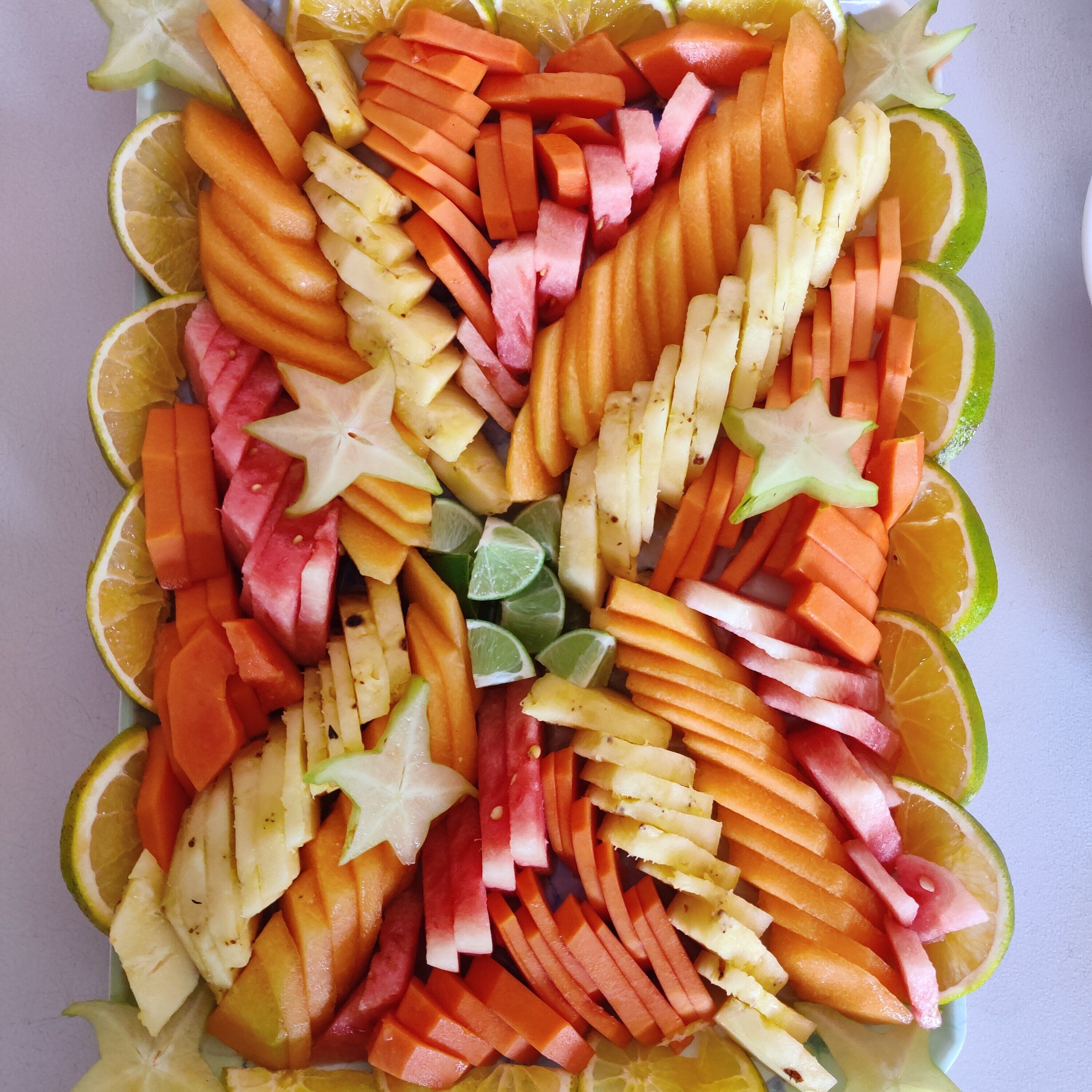 Un assortiment de fruits coupés en tranches, comprenant des pommes, des oranges et des carottes, disposés de manière décorative.
