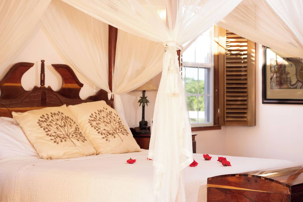 A bedroom with a canopy bed, wooden headboard, and decorative pillows.