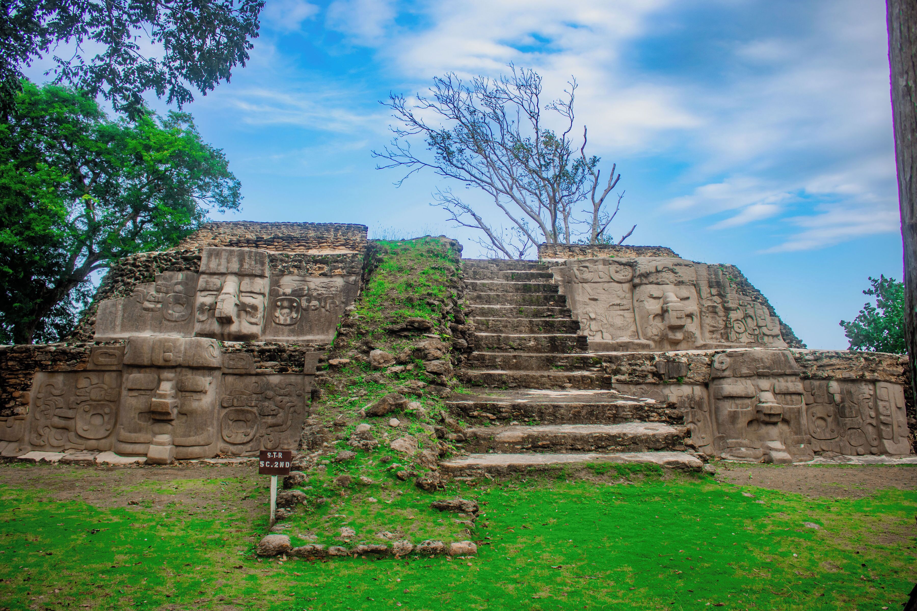 Ancient stone ruins with carved faces and steps leading up to a platform.