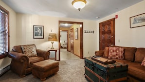 A living room with two leather sofas, a wooden cabinet, and a lamp. - Trainmasters Inn (Palmer)