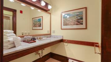 A bathroom with a marble sink, a large mirror, two framed pictures on the wall, and a towel rack.