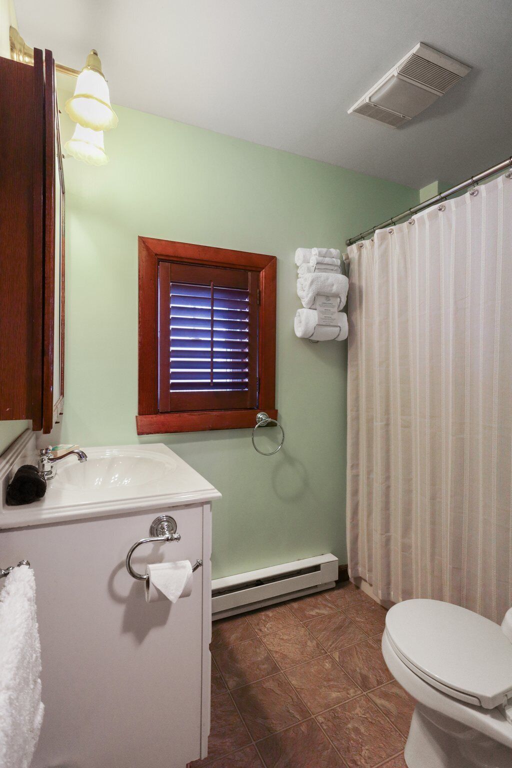 A bathroom with a sink, toilet, and shower curtain.