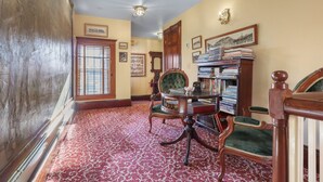 A room with a red patterned carpet, wooden furniture, and a bookshelf filled with books. - Trainmasters Inn (Palmer)